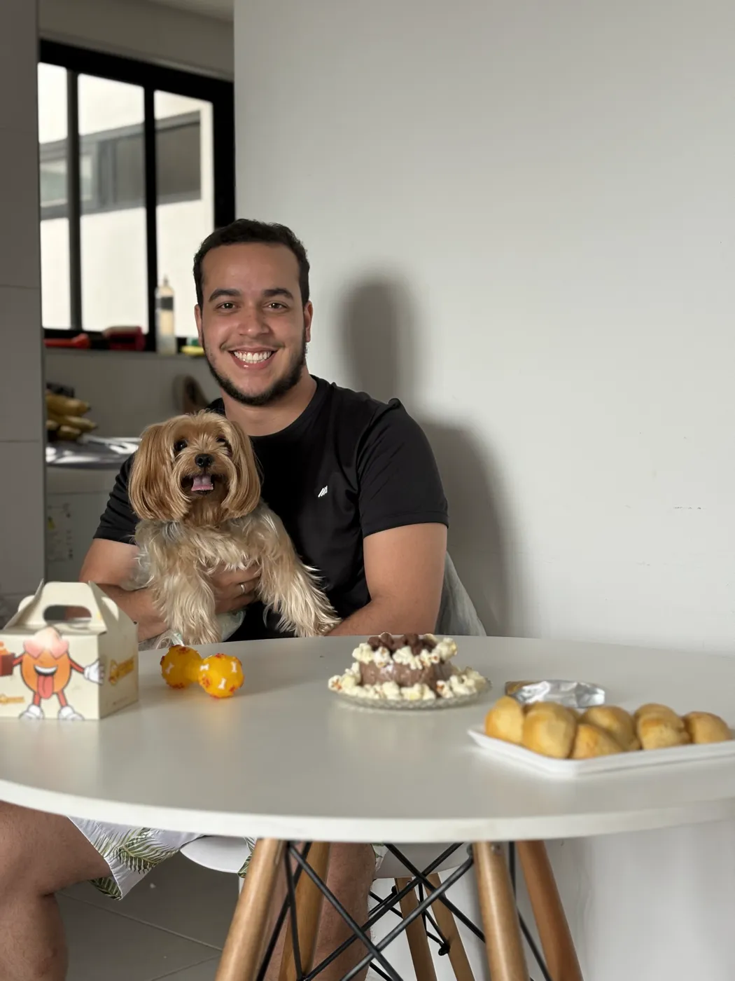 Tarcio Diniz em casa, à mesa, com o cachorro no colo