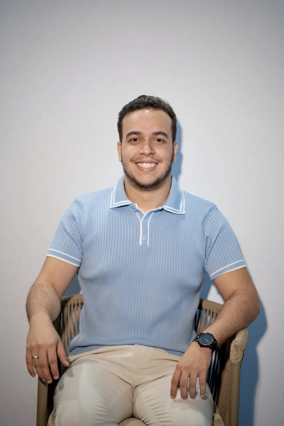Tarcio Diniz sentado, de polo azul, sorrindo