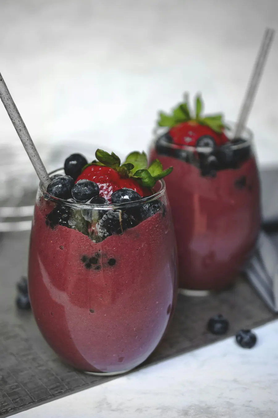 Dois copos de batida de frutas vermelhas com morango e mirtilo