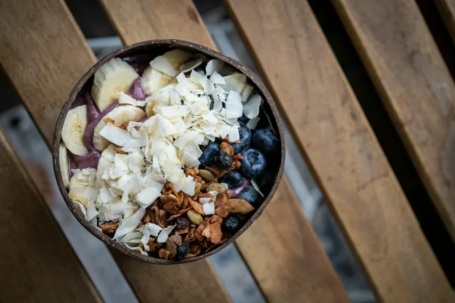 Tigela de casca de coco com açaí, coco em lascas, granola e banana