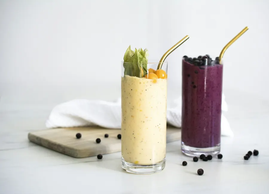 Copos de suco de frutas amarelo e roxo com canudo dourado