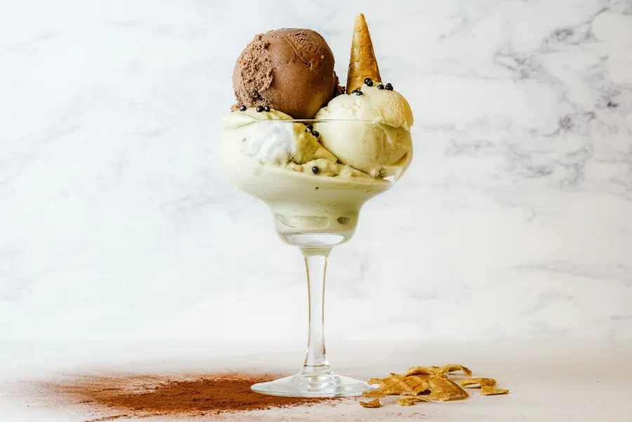 Taça de vidro com bolas de sorvete de creme e chocolate e raspas por cima
