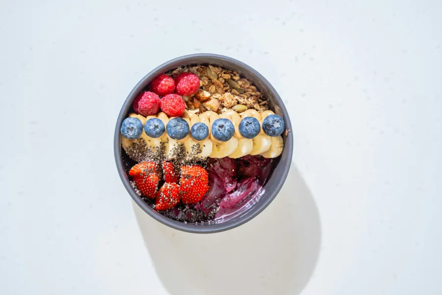 Tigela de açaí vista de cima, com morango, mirtilo e banana em fileira