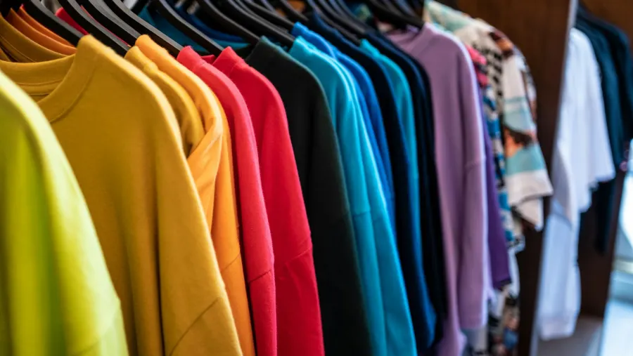 Camisetas de cores variadas penduradas em uma arara