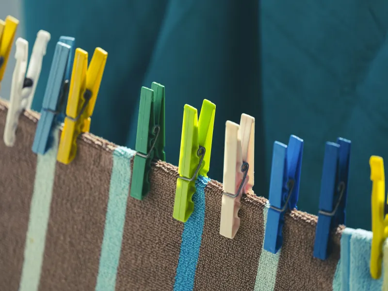Prendedores de roupa coloridos presos em uma toalha listrada