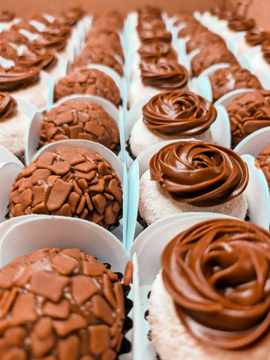 Brigadeiros gourmet em forminhas brancas, uns com granulado de chocolate e outros com bico de brigadeiro mole