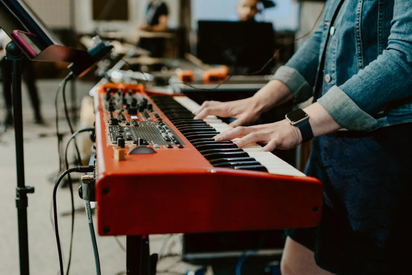 Mãos tocando um teclado vermelho, durante o louvor