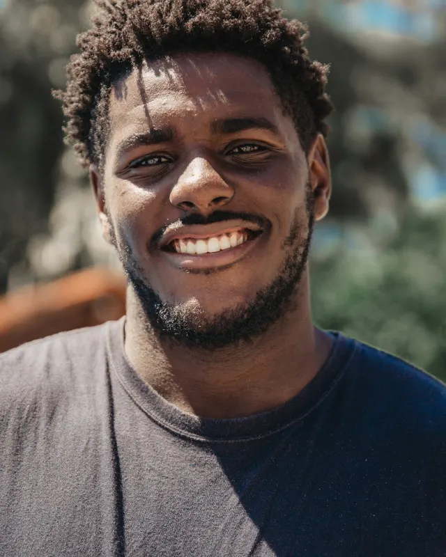 Davi Cavalcanti, de barba curta e camiseta azul-marinho, sorrindo