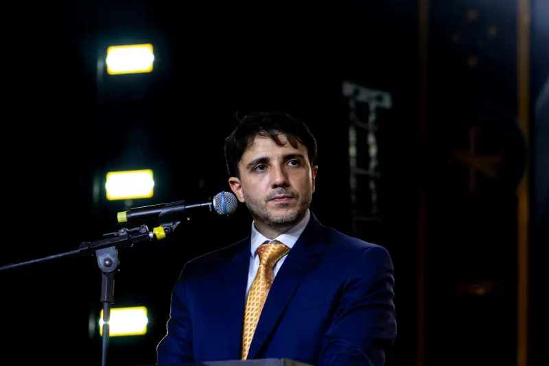 Carlos Veloso, de terno e gravata, diante do microfone
