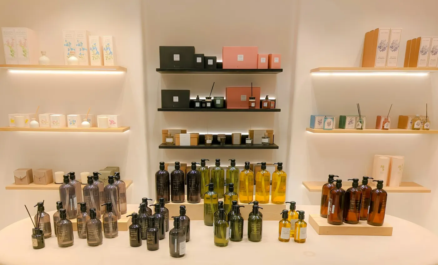 Prateleiras claras de uma loja, com frascos de vidro escuro e caixas de cosméticos organizados em fileiras