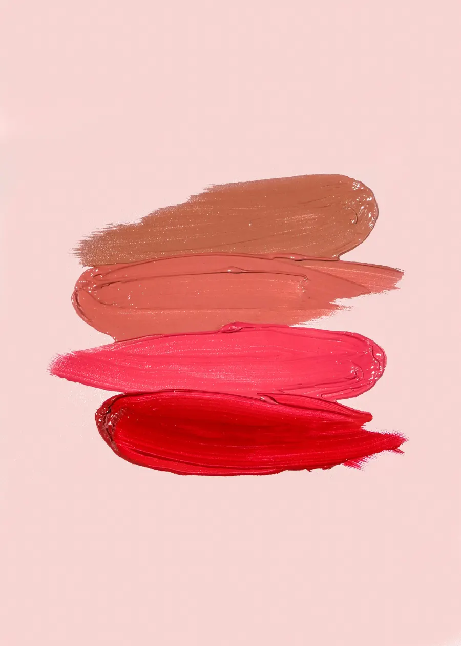 Quatro faixas de batom em tons de nude, coral e vermelho sobre fundo rosa claro