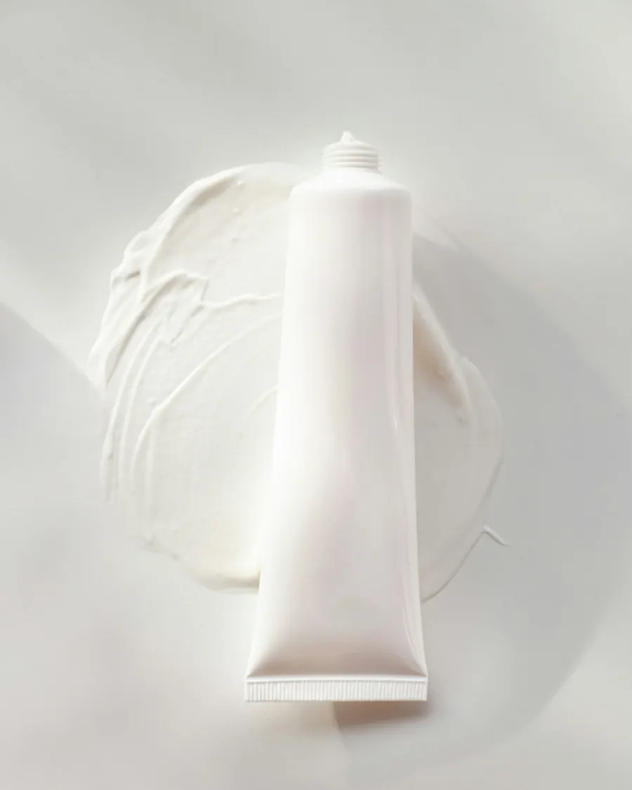 Tubo branco de creme sobre uma pasta branca espalhada