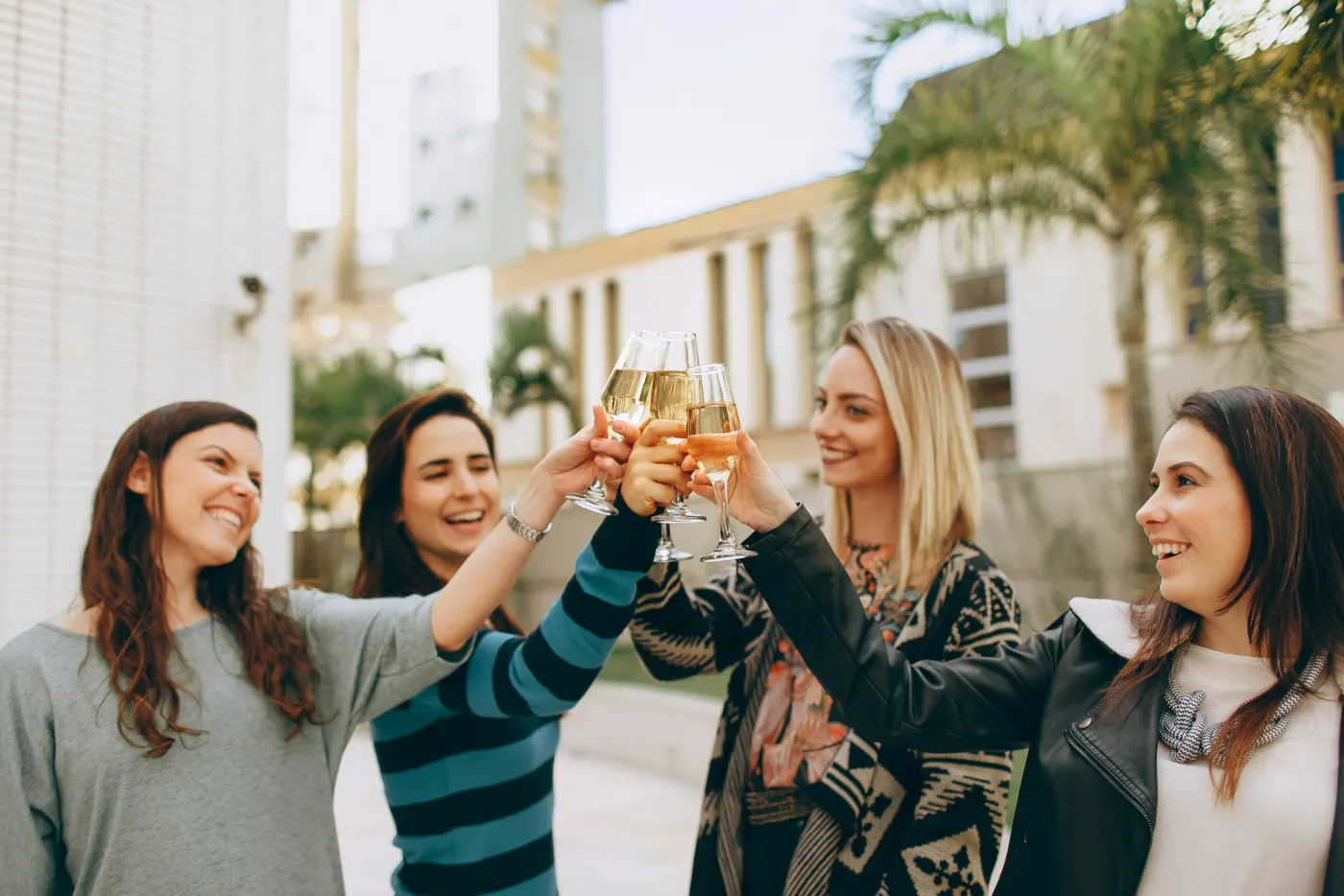 Quatro amigas brindando com taças de espumante ao ar livre