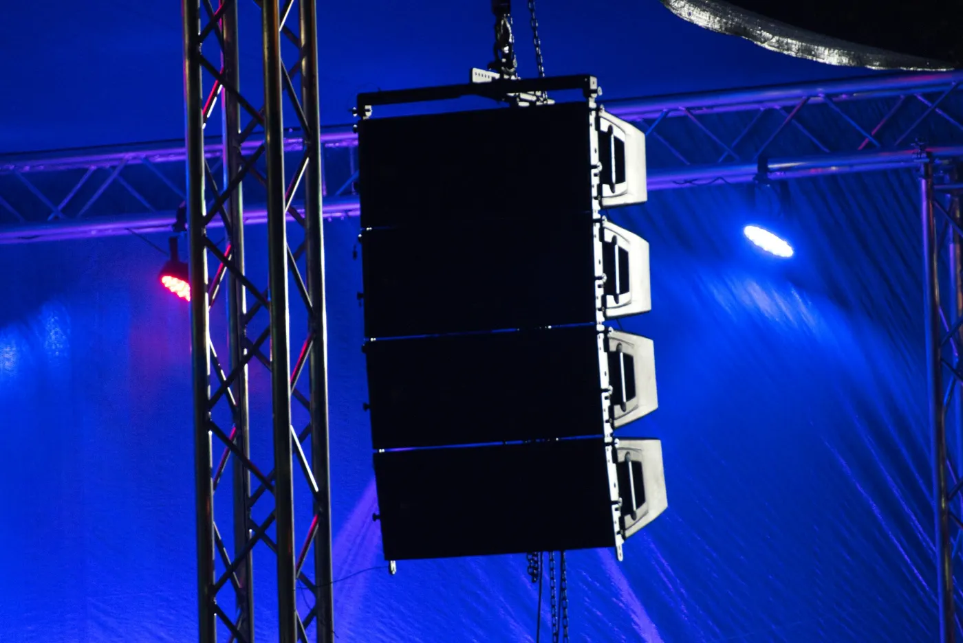 Caixa de som line array pendurada em treliça com luz azul