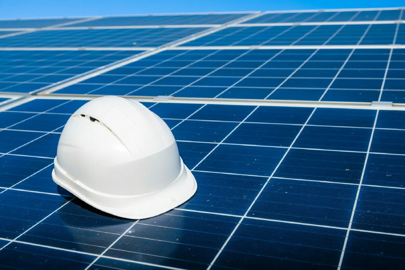 Capacete de obra branco apoiado sobre painéis solares