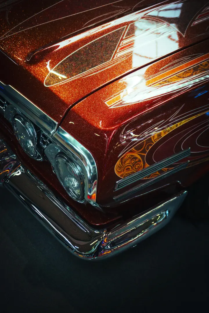 Frente de um carro antigo cor de cobre, com a pintura polida e o cromado brilhando