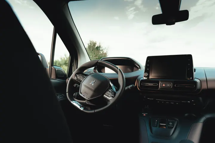 Painel, volante e tela de um carro compacto visto do banco de trás, limpo, com a luz da janela