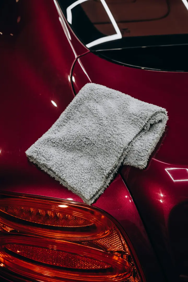 Pano de microfibra cinza sobre a lanterna de um carro vermelho recém-lavado