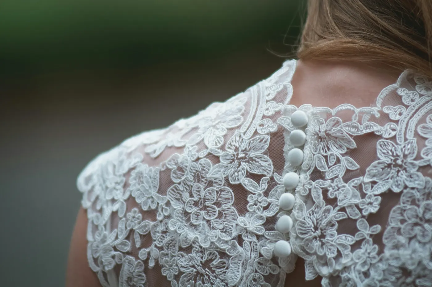 Costas de um vestido de noiva com renda e botões de pérola