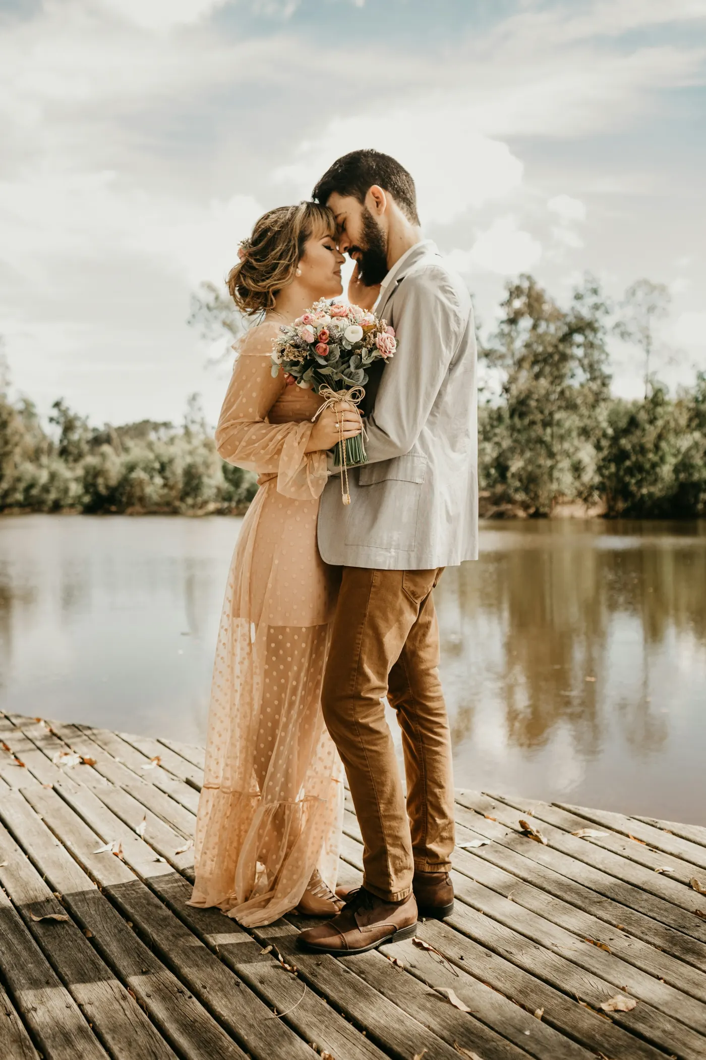 Casal abraçado em um deque de madeira à beira do lago