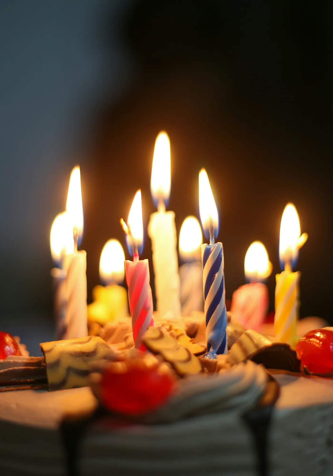 Close de velas acesas sobre um bolo, com a chama em foco