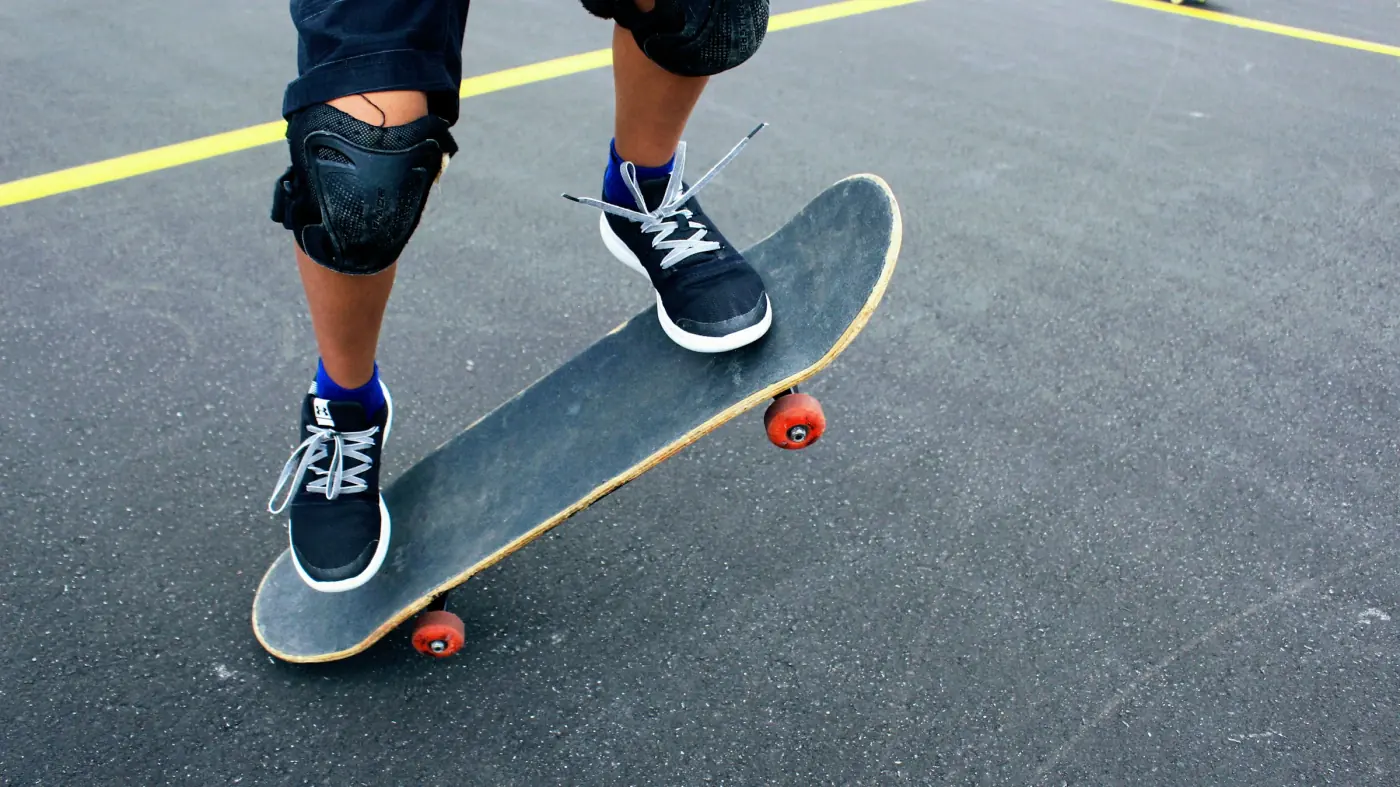 Skatista de tênis escuro em cima do skate no asfalto