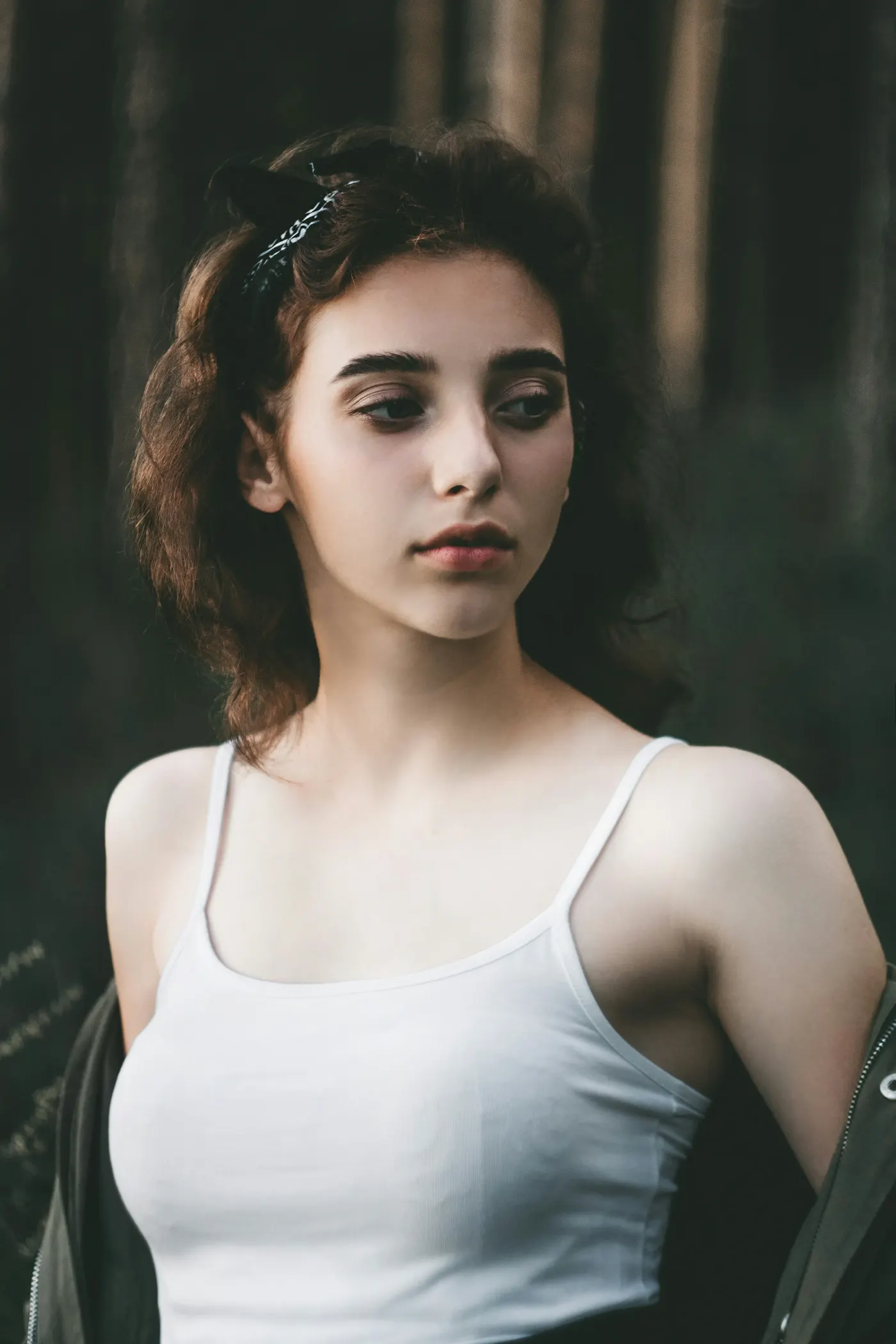 Jovem de blusa branca de alça em um cenário de mata