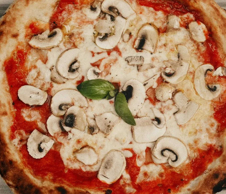 Pizza de champignon com molho de tomate e muçarela, de borda manchada, vista de cima