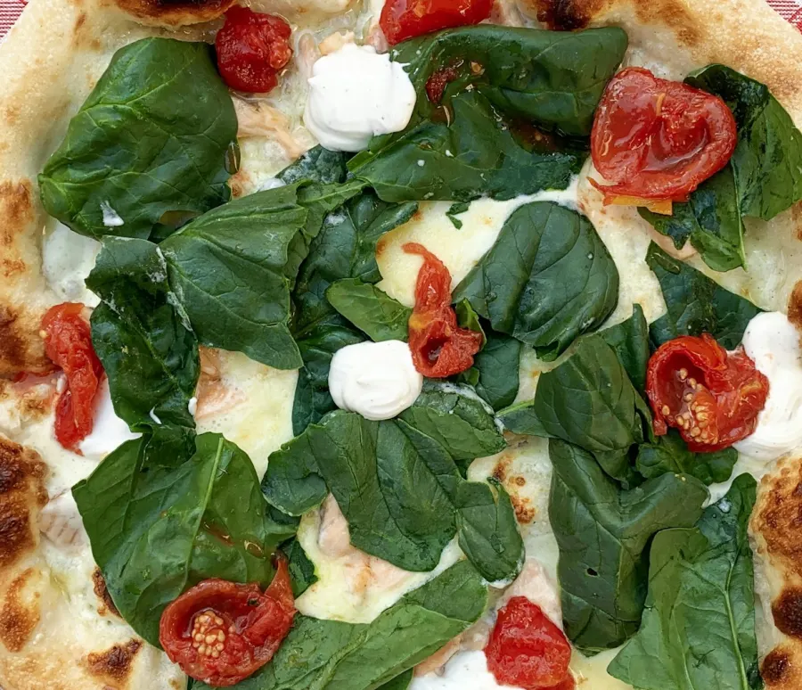 Pizza de espinafre com ricota e tomatinho assado, de borda manchada, vista de cima