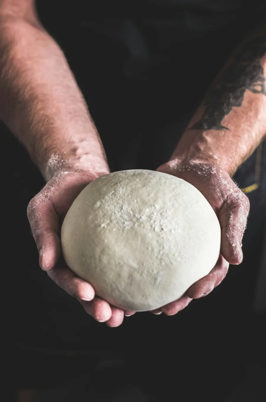 Mãos segurando uma bola de massa de pizza