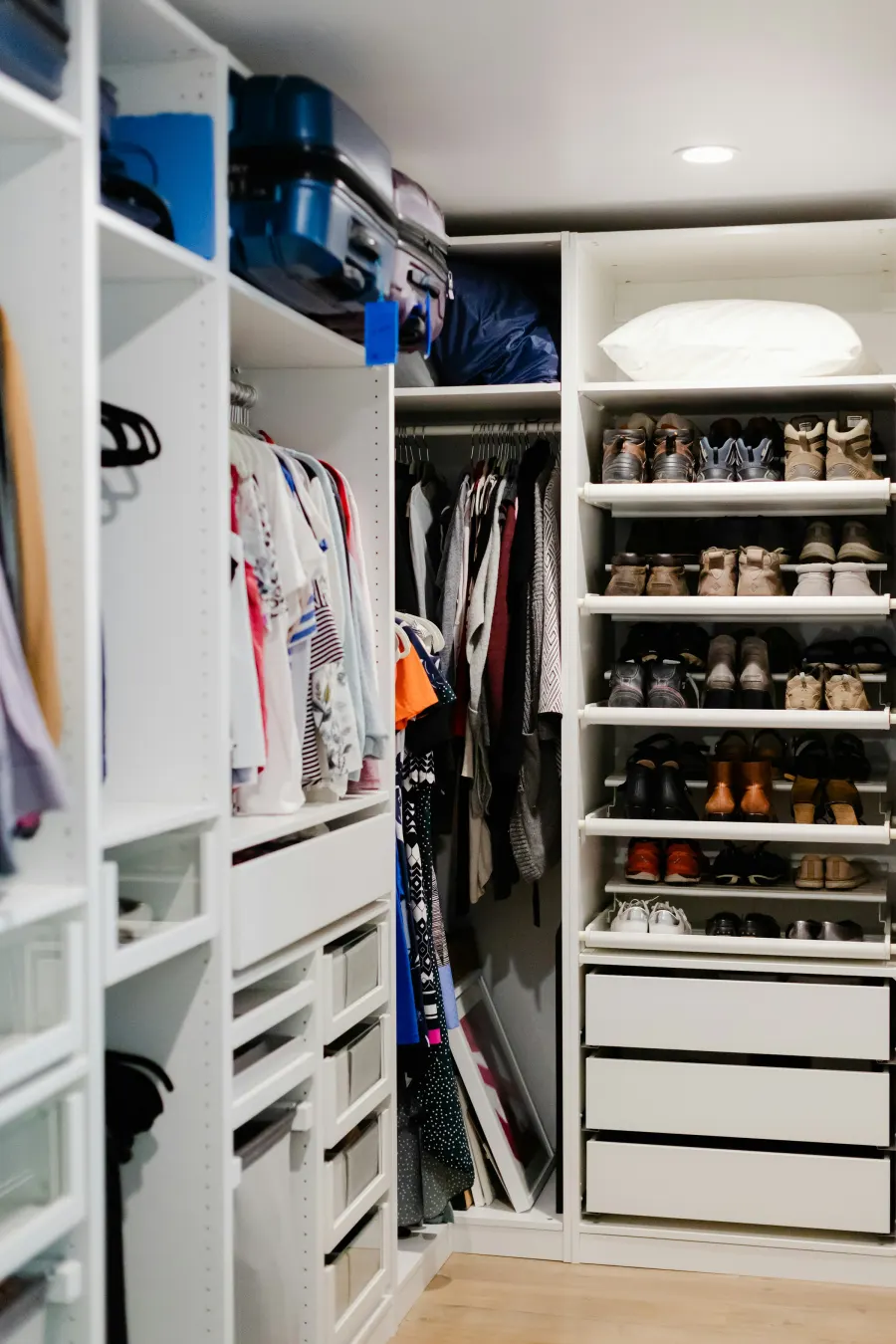 Closet branco com sapateira, cabides e gavetas, visto da porta