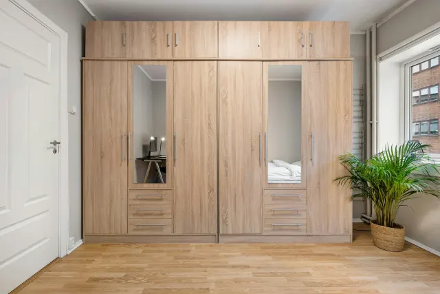 Guarda-roupa de quatro portas em madeira clara, com dois espelhos e gavetas