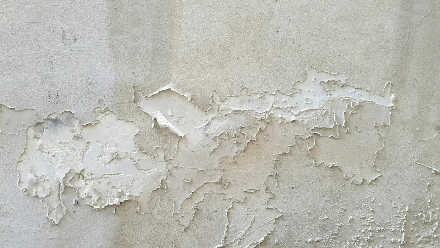 Parede com tinta descascando e massa solta por causa de infiltração
