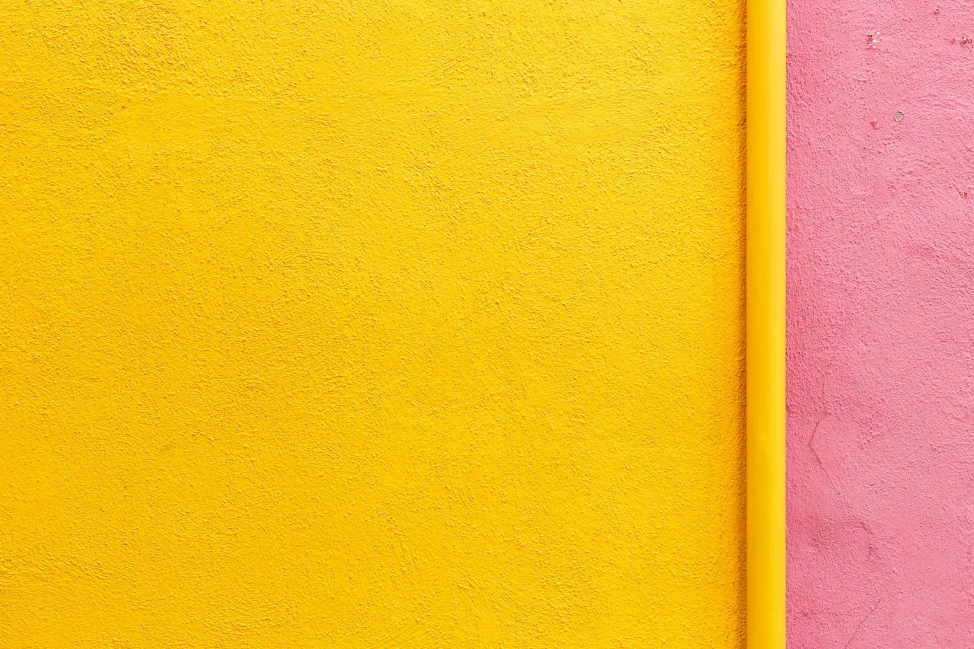 Parede lisa pintada de amarelo, com um friso rosa ao lado