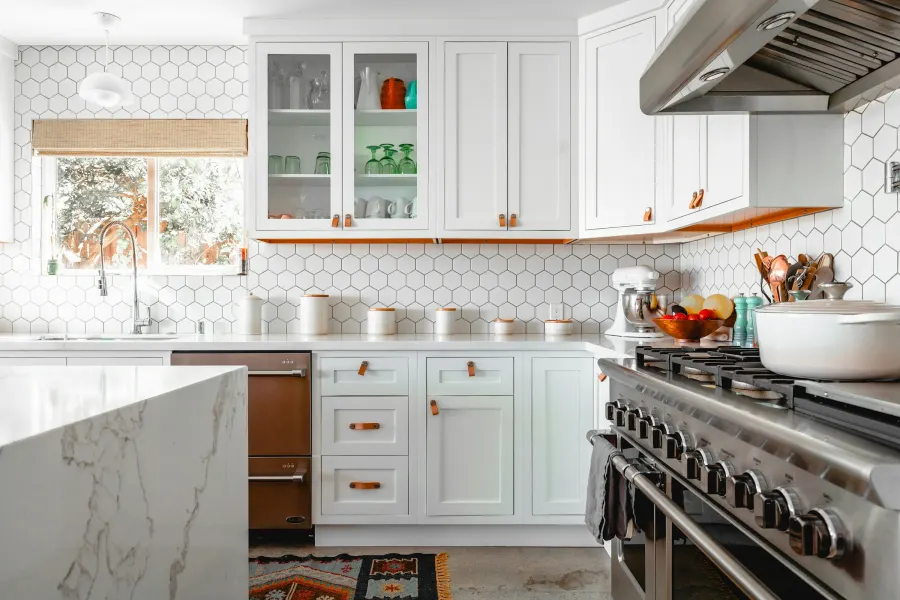 Cozinha reformada com revestimento hexagonal branco, armários claros e fogão de seis bocas